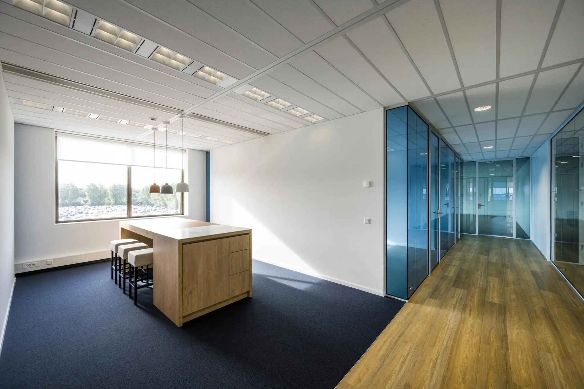 Moderne kantoorruimte op Rotterdam Airportplein met glazen wanden, houten vloer en een vergadertafel bij het raam.